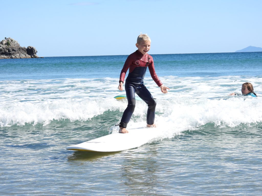 Kid standing up on a wave at holiday surf camp